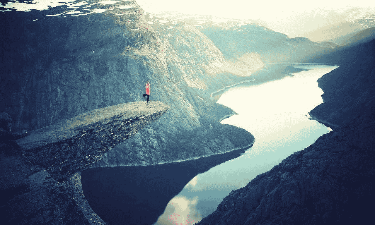 Person standing on a mountain cliff with a breathtaking valley view, symbolizing dreams, goals, and success.