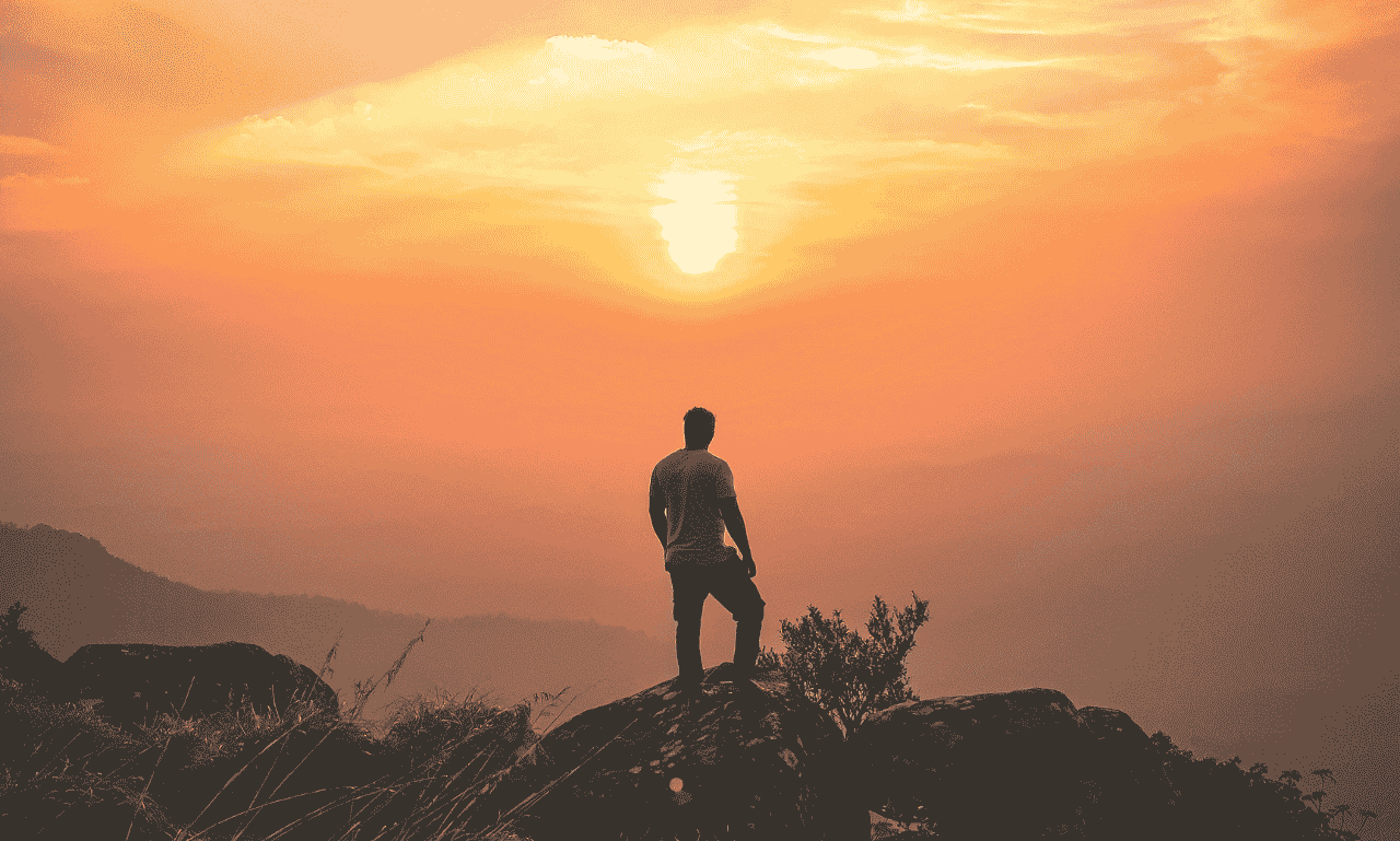 peaceful sunrise with person standing on mountain representing inspiration and new beginnings